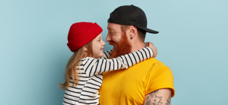 Father wearing a backwards hat holding his daughter 
