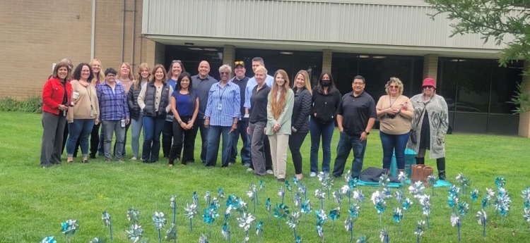 Group of Child, Family, and Adult Services employees standing in front of planted pinwheels