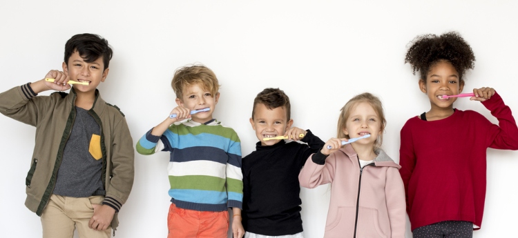 five young children brushing their teeth 
