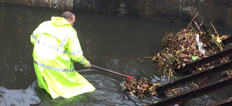 Utility worker clearing debris from a storm drain