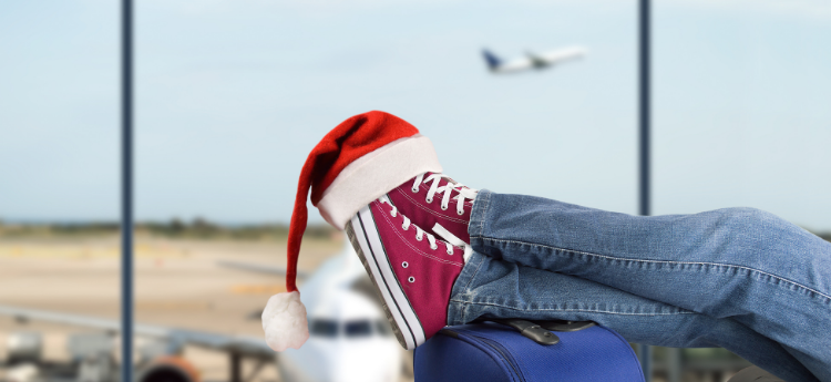 Feet kicked up on a suitcase with a Santa hat on top 