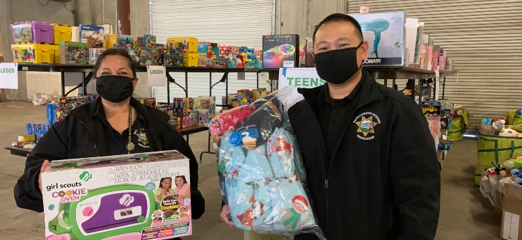Two employees holding gifts while volunteering with a gift drive