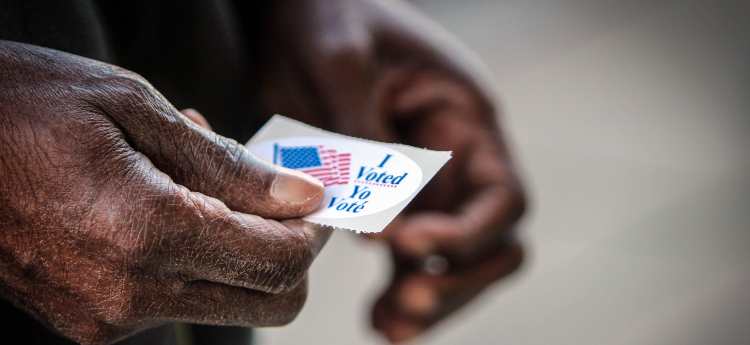 Hand holding an "I Voted/Yo Vote" Sticker