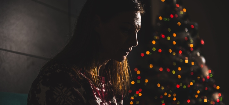 Woman in a dark room with a Christmas tree in the background
