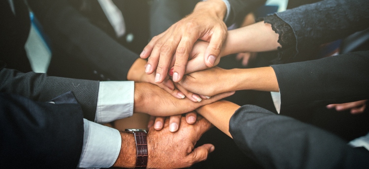 Group of hands together at the center of a huddle