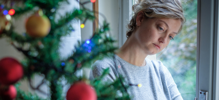 Sad looking woman near a Christmas tree