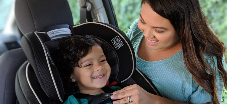 Mother buckling child into car seat