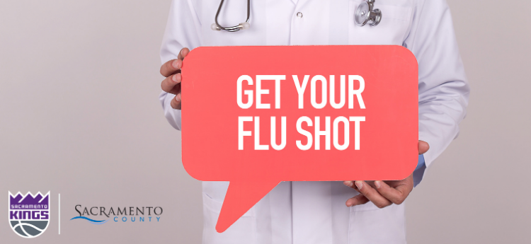 Doctor holding sign reading "Get Your Flu Shot"