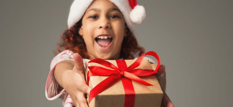 Young girl wearing a Santa Claus hat holding a present. 