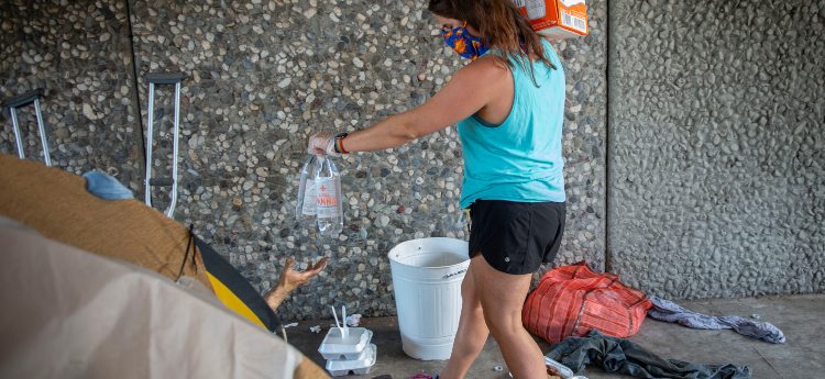 Woman handing out water to a person in a tent