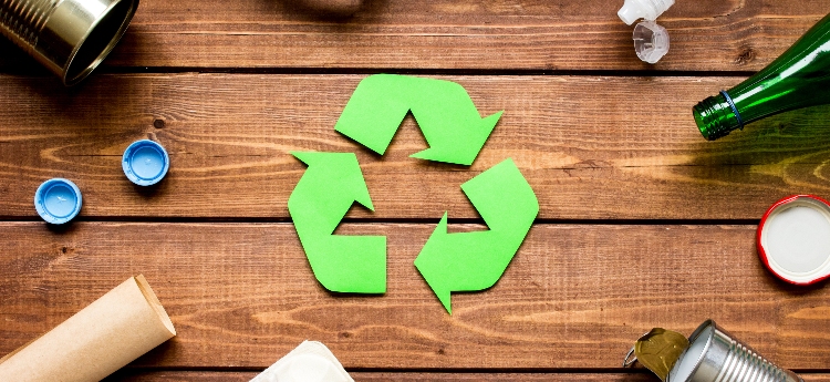Triangular Recycling Image on a wooden background surrounded by recyclable materials 