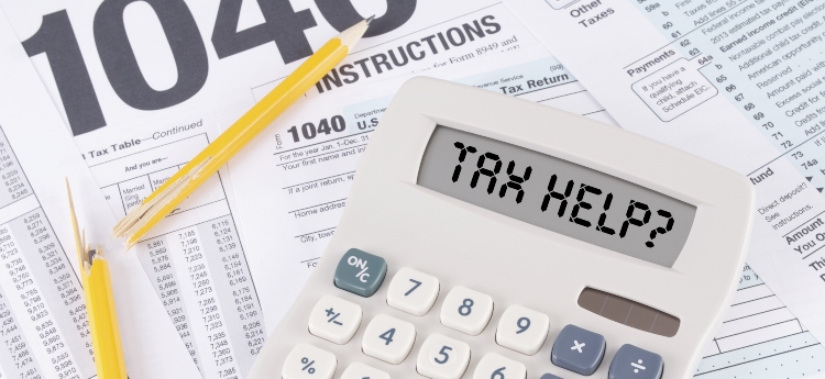 A calculator that reads "Tax Help?" sits atop scattered tax forms 