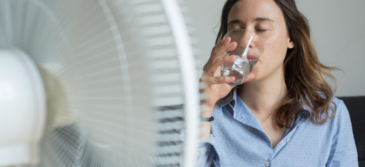 Woman Driking a glass of water in front of a fan