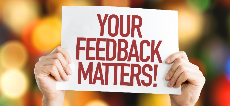 Hands holding up a sign that reads "Your Feedback Matters" 