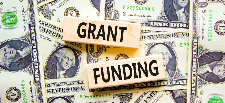 Photo of cash with two wooden blocks on top that say Grant Funding